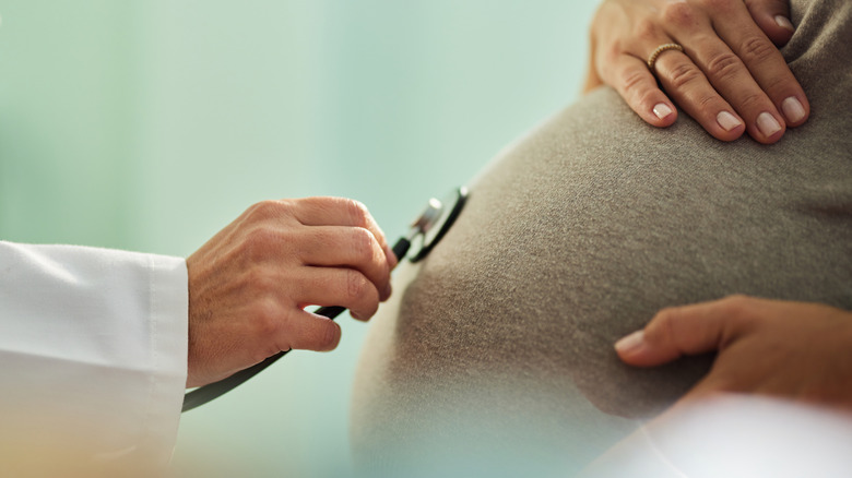 doctor listening to pregnant woman's stomach