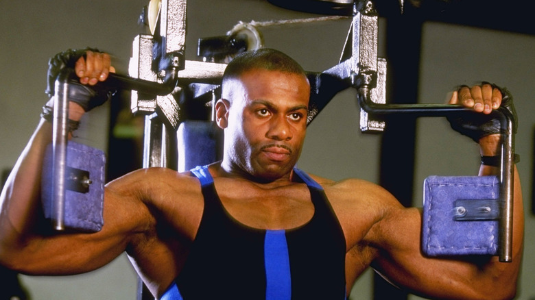 young man doing reps on an arm exercise machine in a 1990s gym