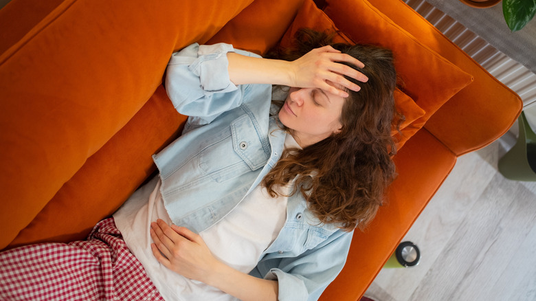Woman clutching her head while lying down