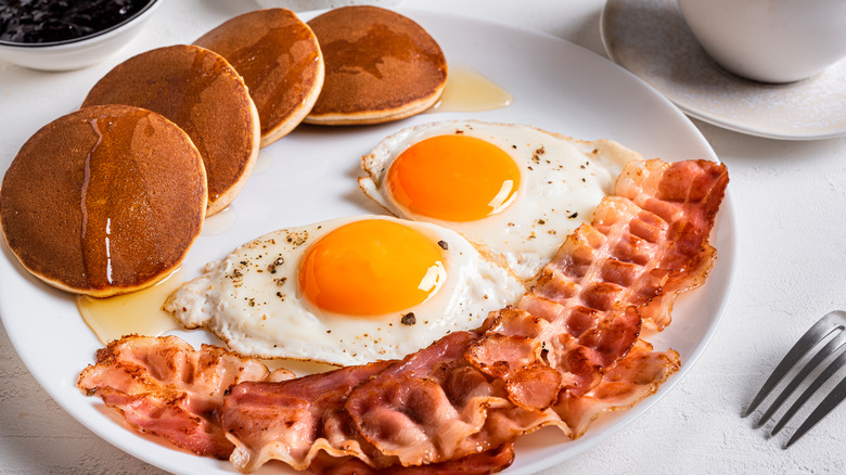 A plate of bacon, eggs, and pancakes