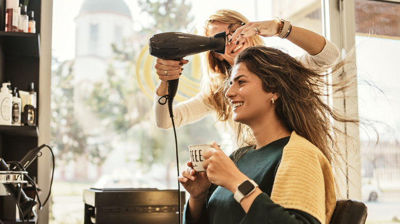 Client's long hair blowing in the wind as hairdresser is blowdrying it