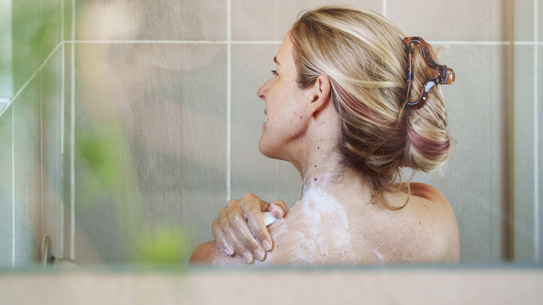 woman in a shower using a bar of soap to get clean