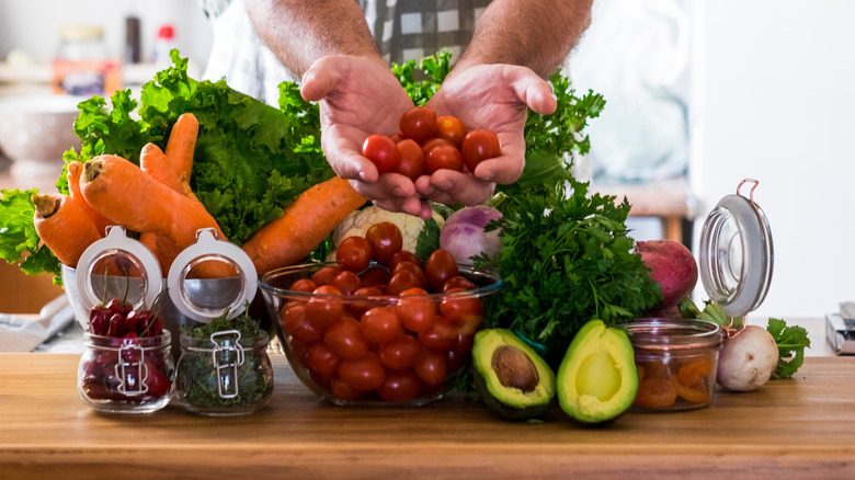 man holding fresh vegetables in a kitchen setting