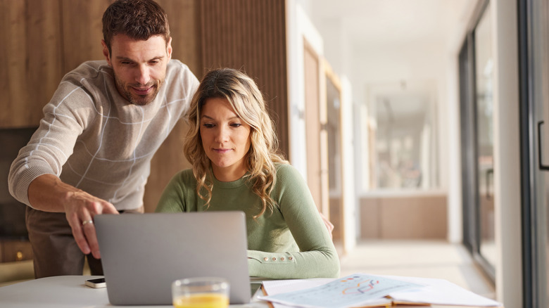 couple reading information together on a laptop at home