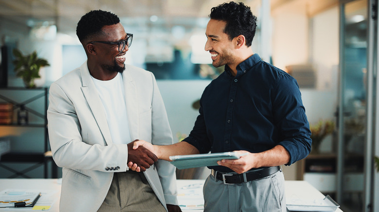 two business men shaking hands as they look at documents