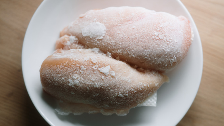 Frozen chicken breasts defrosting on a dish