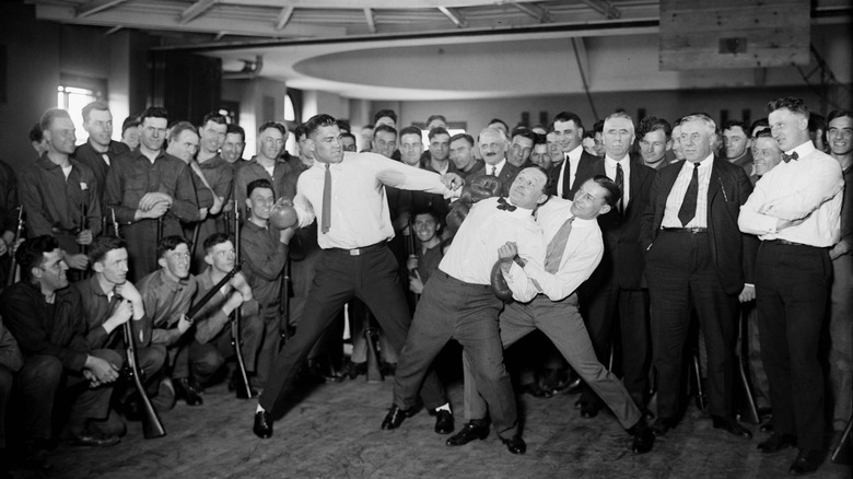 Harry Houdini bracing for impact while boxer Benny Leonard and Jack Dempsey prepare to swing