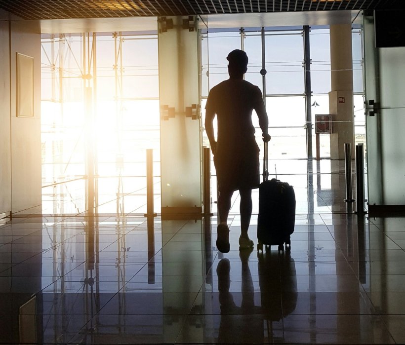 Silhouette of a man at an airport terminal with his luggage